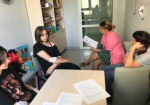 dookoła stołu siedzą pacjenci szpitala. nauczycielka czyta tekst książki