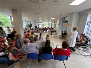 dzieci siedzace w holu szpitalnym sluchajace koncertu