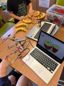 Dzieci grają na łyżkach i banach podłączonych do komputera za pomocą zestawów MakeyMakey